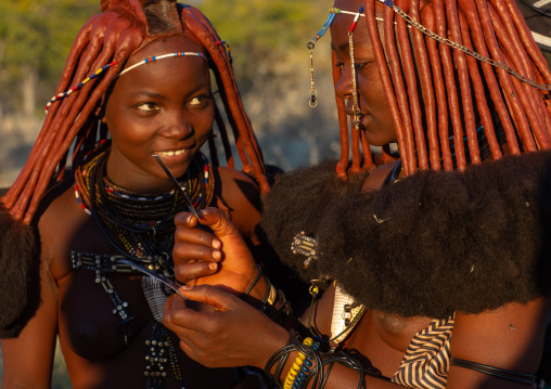 Himba tribe women looking at polaroids, Cunene Province, Oncocua, Angola