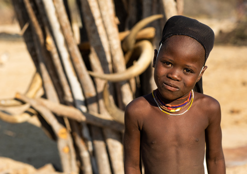 Mucubal tribe girl in front of a totem with cow horns, Namibe Province, Virei, Angola