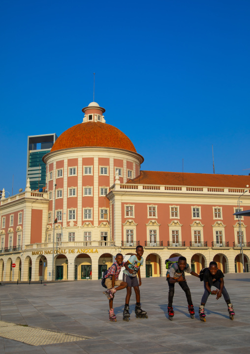 Angolan teenage boys wirth roller skating in front of banco nacional de angola, Luanda Province, Luanda, Angola