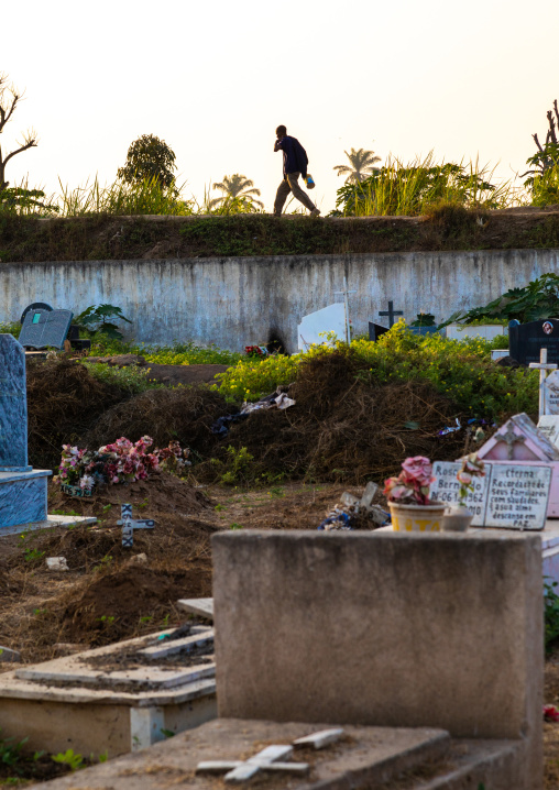 Angolan man walking o the wall of an old cemetery, Benguela Province, Catumbela, Angola