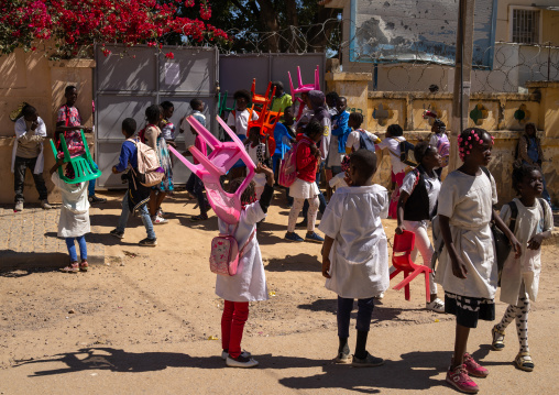 Angolan children carrying her own chairs to go to school, Huila Province, Lubango, Angola