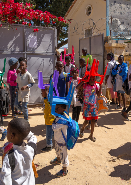 Angolan children carrying her own chairs to go to school, Huila Province, Lubango, Angola