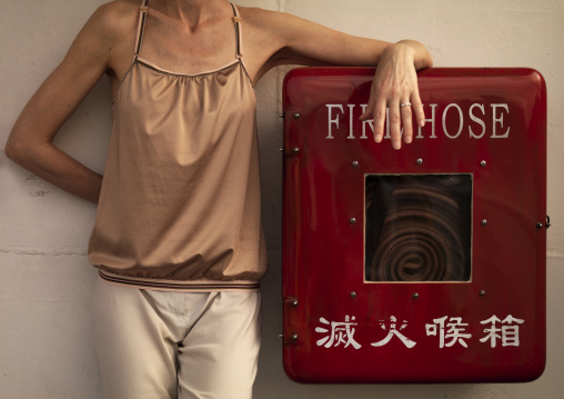 Woman Standing On Fire Hose On A Ferry, Hong Kong, China