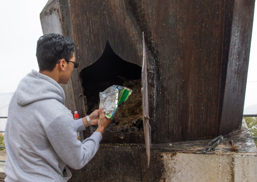 Tibetan man burning some barley seeds in an oven in Shachong monastery, Qinghai Province, Wayaotai, China