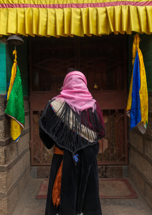 Tibetan woman with braided hair praying in Shachong monastery, Qinghai Province, Wayaotai, China