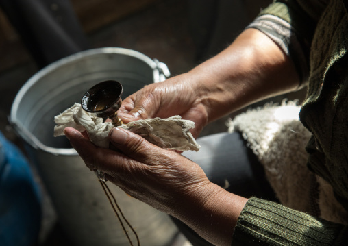 tibetan Volunteer cleaning a butter lamp in Shachong monastery, Qinghai Province, Wayaotai, China