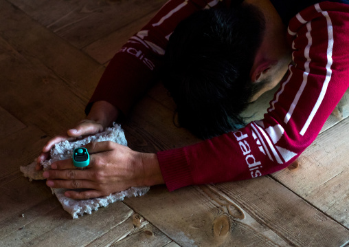 Tibetan pilgrim with mini hand tally counter praying and prostrating in Rongwo monastery, Tongren County, Longwu, China