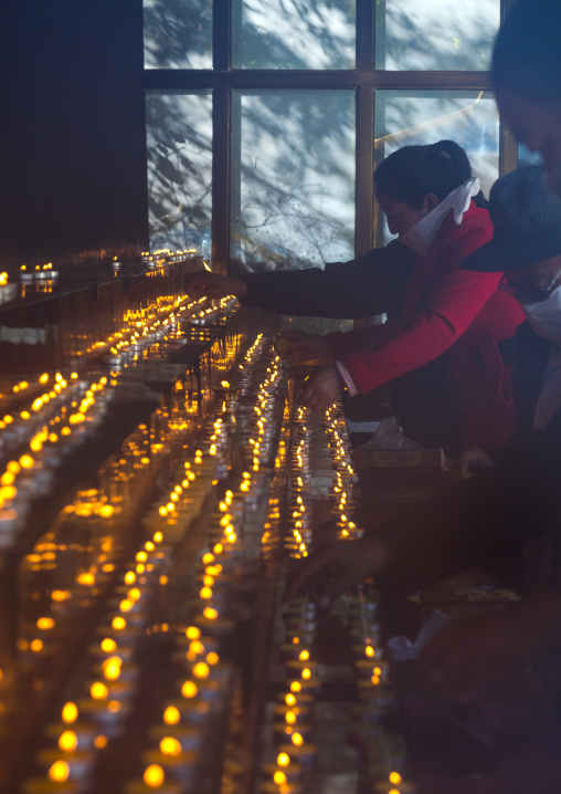 Tibetan pilgrims position butter lamps at Rongwo monastery, Tongren County, Longwu, China