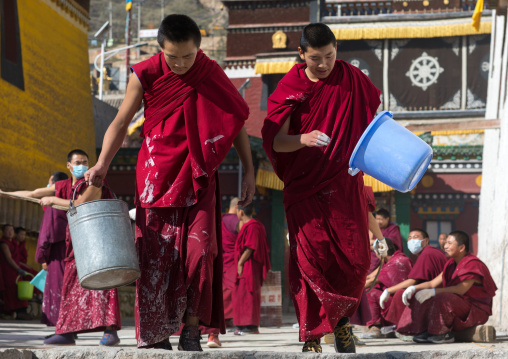 Monks carrying buckets for the painting of a temple in Rongwo monastery, Tongren County, Longwu, China