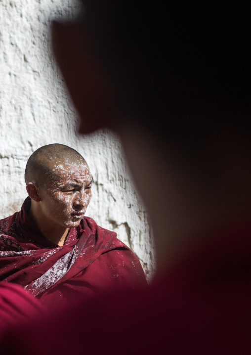 tibetan Monk with white painting on his face while renovating the walls of a temple in Rongwo monastery, Tongren County, Longwu, China