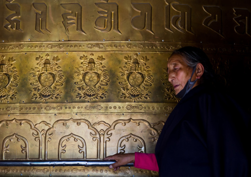 Tibetan pilgrim turning huge prayer wheel in Rongwo monastery, Tongren County, Longwu, China