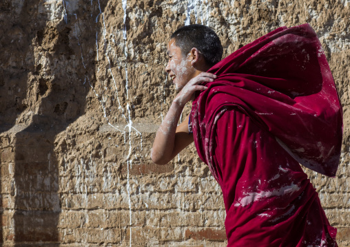 Tibetan monk enjoying a water fight after the yearly renovation of the Rongwo monastery, Tongren County, Longwu, China