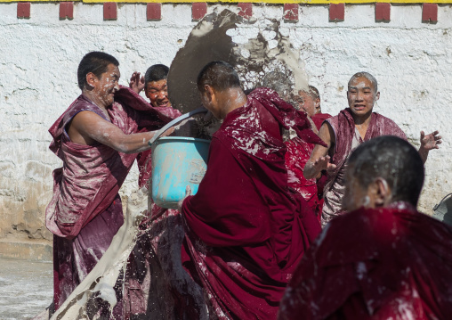 Tibetan monks enjoying a water fight after the yearly renovation of the Rongwo monastery, Tongren County, Longwu, China