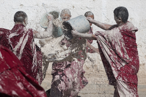 Tibetan monks enjoying a water fight after the yearly renovation of the Rongwo monastery, Tongren County, Longwu, China