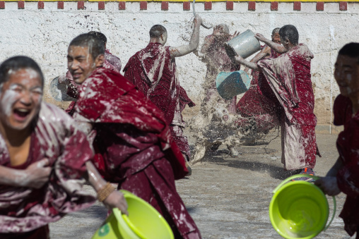 Tibetan monks enjoying a water fight after the yearly renovation of the Rongwo monastery, Tongren County, Longwu, China