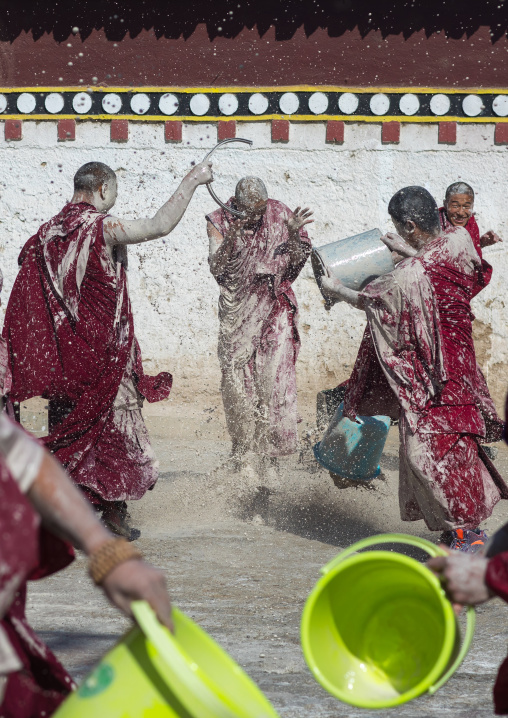 Tibetan monks enjoying a water fight after the yearly renovation of the Rongwo monastery, Tongren County, Longwu, China