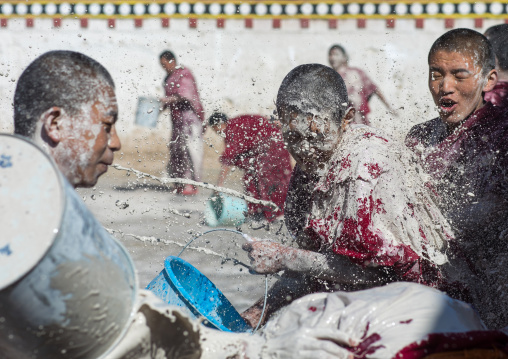 Tibetan monks enjoying a water fight after the yearly renovation of the Rongwo monastery, Tongren County, Longwu, China