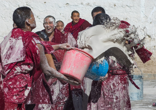 Tibetan monks enjoying a water fight after the yearly renovation of the Rongwo monastery, Tongren County, Longwu, China