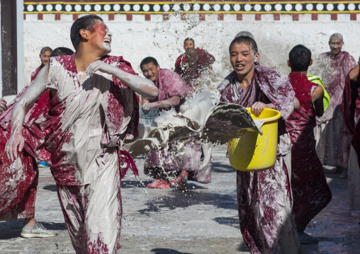 Tibetan monks enjoying a water fight after the yearly renovation of the Rongwo monastery, Tongren County, Longwu, China