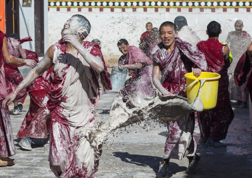 Tibetan monks enjoying a water fight after the yearly renovation of the Rongwo monastery, Tongren County, Longwu, China