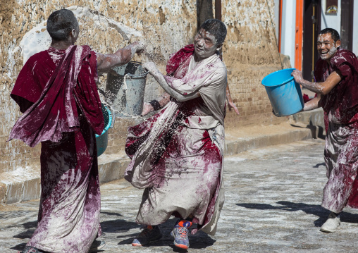 Tibetan monks enjoying a water fight after the yearly renovation of the Rongwo monastery, Tongren County, Longwu, China