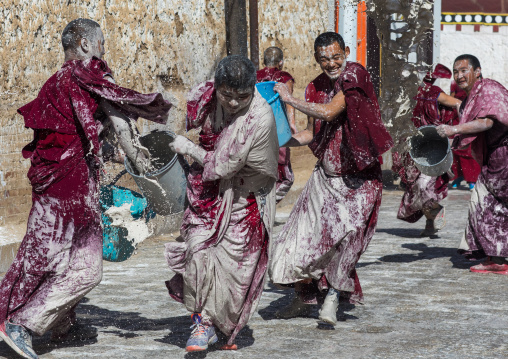 Tibetan monks enjoying a water fight after the yearly renovation of the Rongwo monastery, Tongren County, Longwu, China