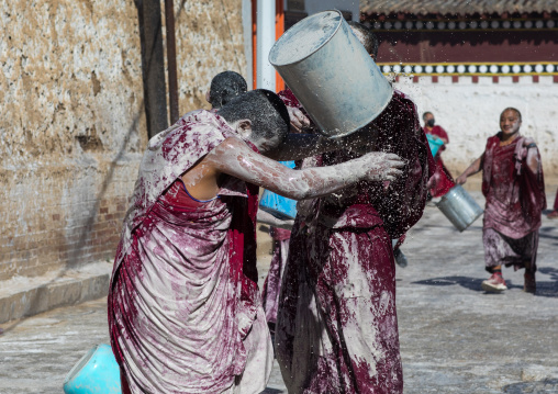 Tibetan monks enjoying a water fight after the yearly renovation of the Rongwo monastery, Tongren County, Longwu, China