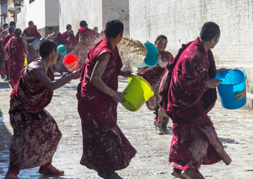 Tibetan monks enjoying a water fight after the yearly renovation of the Rongwo monastery, Tongren County, Longwu, China