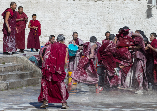 Tibetan monks enjoying a water fight after the yearly renovation of the Rongwo monastery, Tongren County, Longwu, China