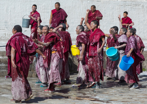 Tibetan monks enjoying a water fight after the yearly renovation of the Rongwo monastery, Tongren County, Longwu, China