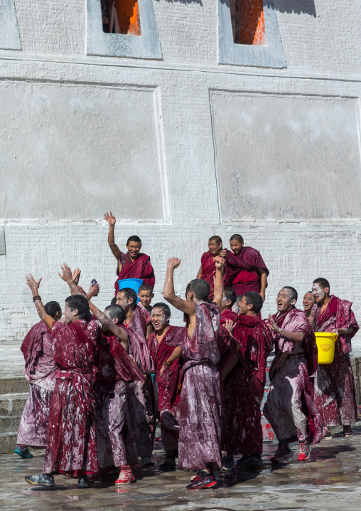 Tibetan monks enjoying a water fight after the yearly renovation of the Rongwo monastery, Tongren County, Longwu, China