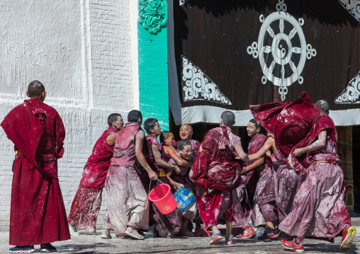 Tibetan monks enjoying a water fight after the yearly renovation of the Rongwo monastery, Tongren County, Longwu, China