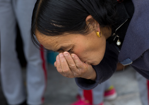 Tibetan woman drinking pepsi cola which has been blessed by the lamas in Rongwo monastery, Tongren County, Longwu, China