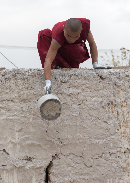 tibetan Monk painting the wall of a temple in Rongwo monastery, Tongren County, Longwu, China