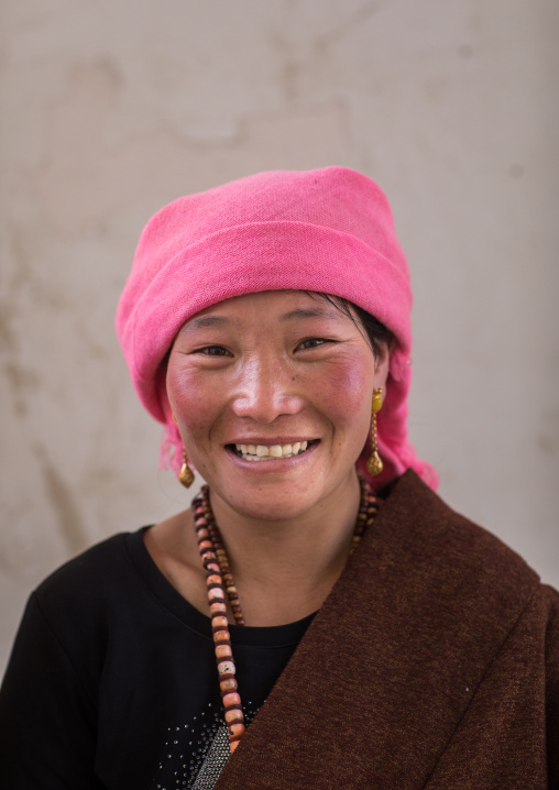 Portrait of a tibetan nomad woman with a pink headwear, Qinghai province, Tsekhog, China