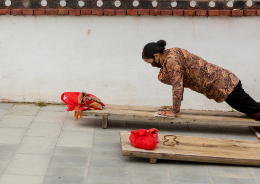 Tibetan pilgrim woman praying and prostrating in Hezuo monastery, Gansu province, Hezuo, China