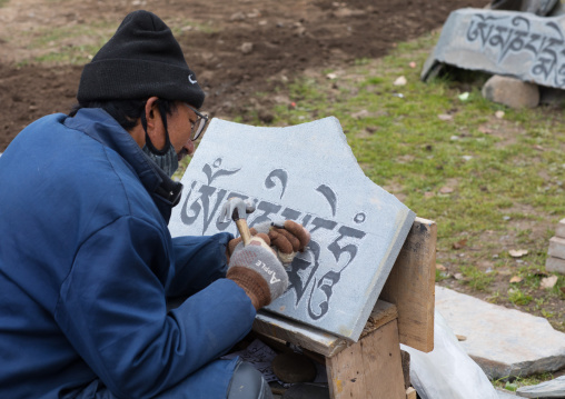 Buddhist man is carving a mani stoni stone in Hezuo monastery, Gansu province, Hezuo, China