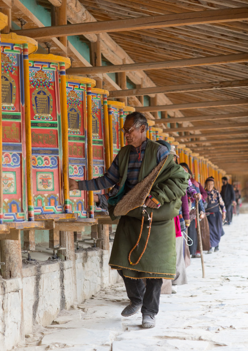 Tibetan pilgrims turning huge prayer wheels in Labrang monastery, Gansu province, Labrang, China