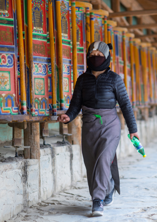 Tibetan pilgrim turning huge prayer wheels in Labrang monastery, Gansu province, Labrang, China