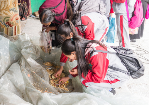 Tibetan teenagers eating remainings of food which has been blessed by the lamas in Rongwo monastery, Tongren County, Longwu, China