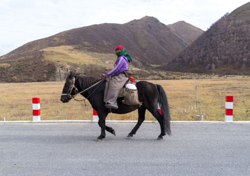 Tibetan woman on her horse, Qinghai province, Sogzong, China