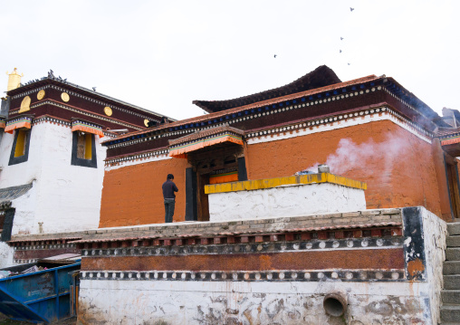 Tibetan man praying in front of a temple in Hezuo  monastery, Gansu province, Hezuo, China