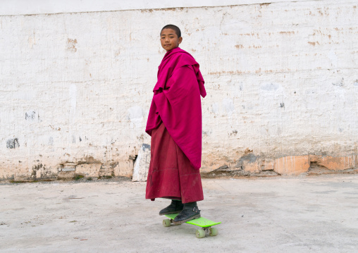 Young tibetan monk on a skateboard in Lhachub monastery, Gansu province, Lhachub, China