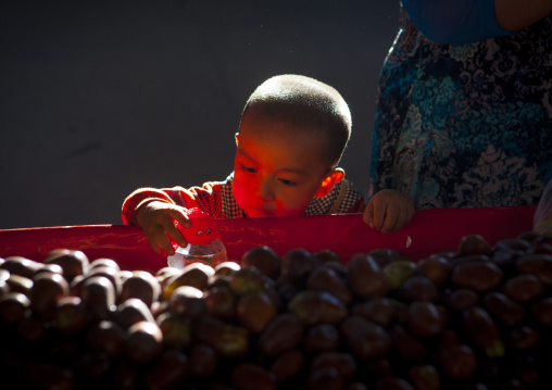 Uyghur Kid Playing Near Piles Of Dates, Kashgar,  Xinjiang Uyghur Autonomous Region, China