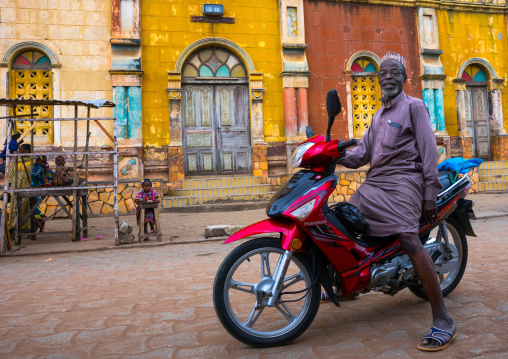 Benin, West Africa, Porto-Novo, old muslim man on a scooter in front of the multicoloured great mosque