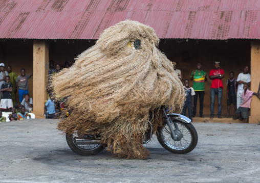 Benin, West Africa, Porto-Novo, zangbeto guardian of the night spirit riding motorcycle in the royal palace