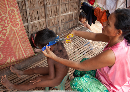 Cambodian mother cutting the hair of her son in the floating village on Tonle Sap lake, Siem Reap Province, Chong Kneas, Cambodia