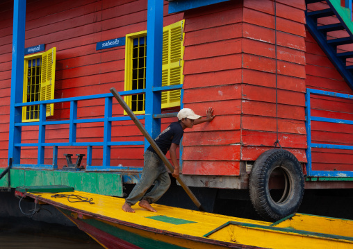 Boy pushing his boat in the floating village on Tonle sap lake, Siem Reap Province, Chong Kneas, Cambodia