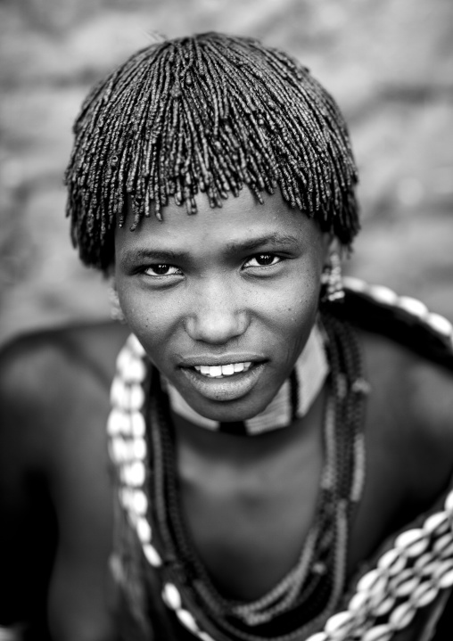 Portrait Of Traditionally Dressed Hamer Beautiful Woman Posing In Front Of Clay House  Omo Valley Ethiopia