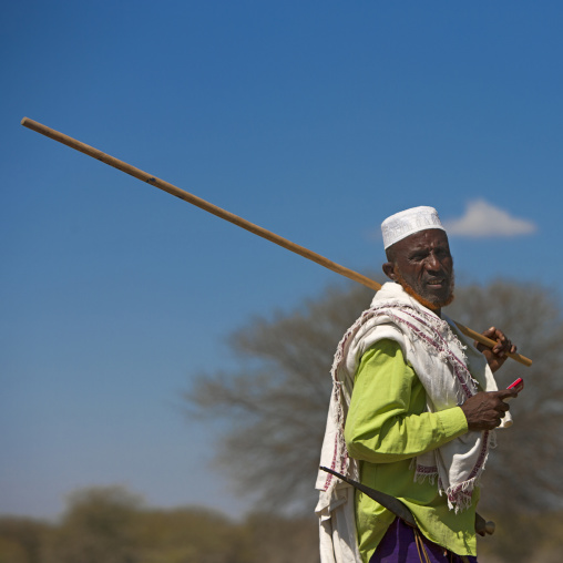 Portrait Of Karrayyu Tribe Elder With Ginger Tainted Beard, Mobile Phone And Long Stick During Gadaaa Ceremony, Metahara, Ethiopia